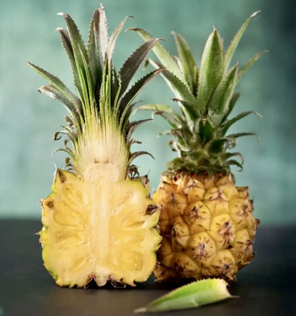 A whole pineapple beside one cut in half